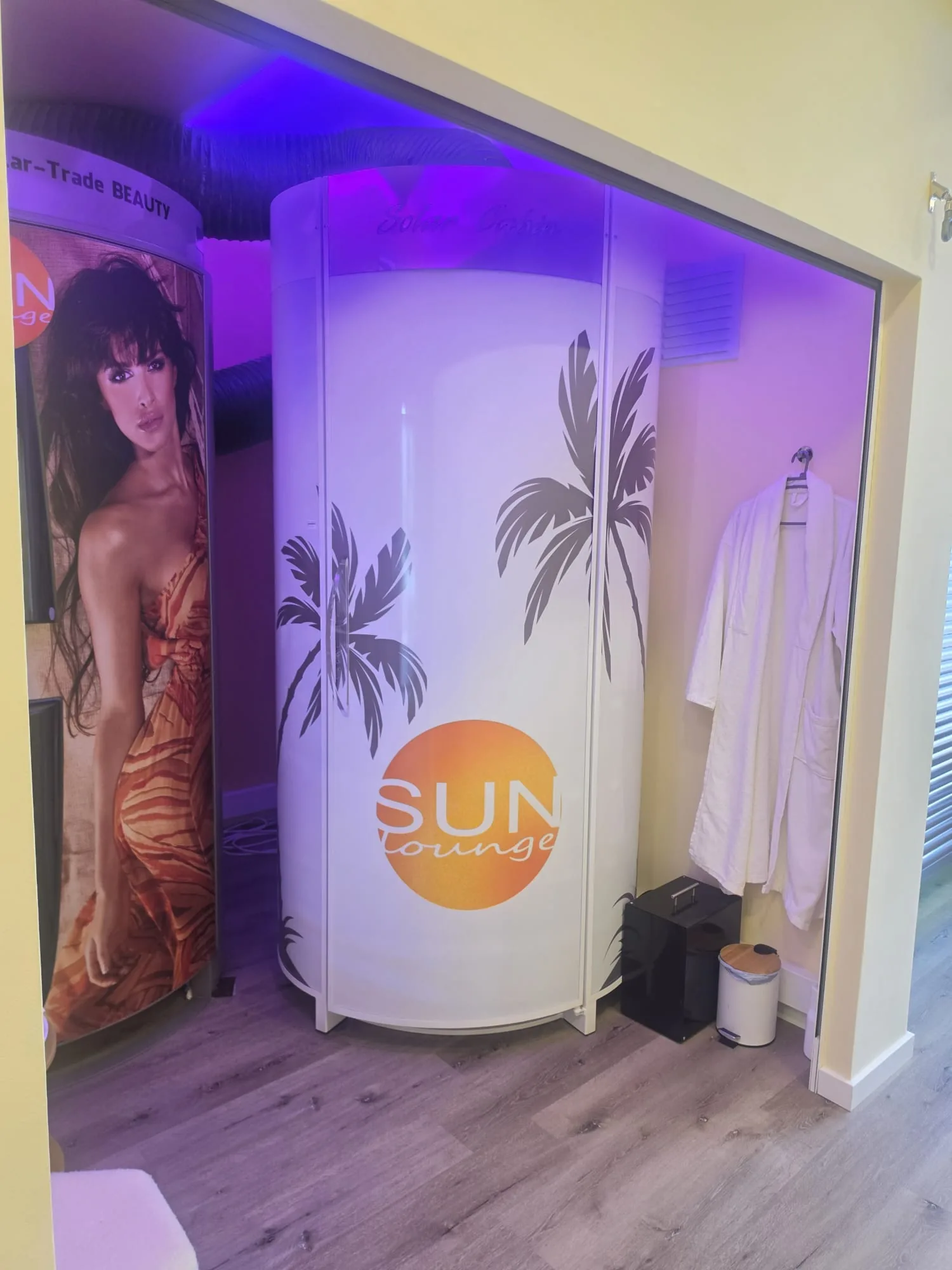 Cabine de solário vertical com logótipo Sun Lounge e roupão